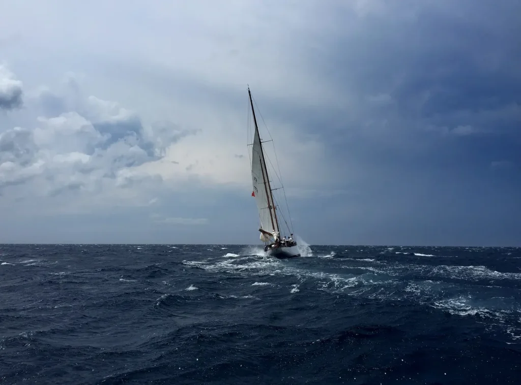 A yacht heeling hard in rough open water under a storm sky