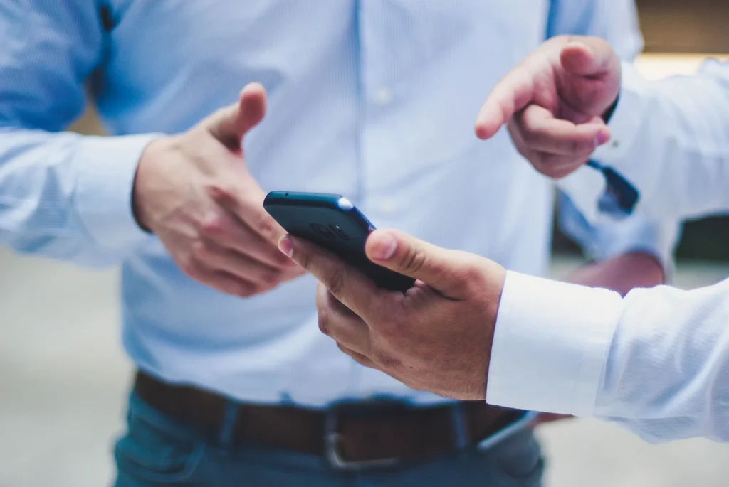 Two people in shirtsleeves conferring over a phone held between them